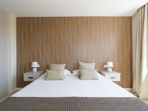 a bedroom with a large white bed with a striped wall at Salobre Golf Villas Kaiman in Salobre