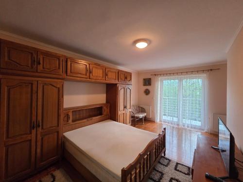 ein Schlafzimmer mit einem Bett, Holzschränken und einem Fenster in der Unterkunft SaDa Centar in Apatin
