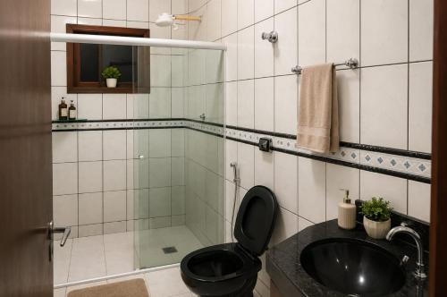 a bathroom with a black toilet and a sink at Pousada Economia in Paracatu