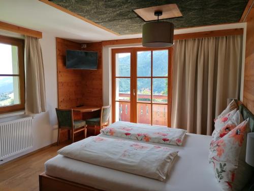 a bedroom with a bed and a desk and windows at Kirchenbichlerhof in Pruggern