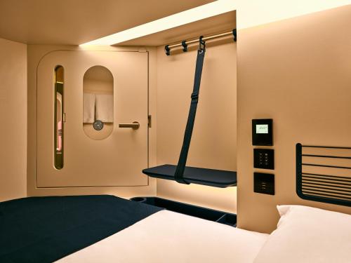 a small room with a bed and a shelf at Otherwander Soho Pod Hotel in London