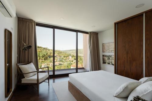 a bedroom with a bed and a chair and a large window at Serpa Pinto Village - Private Pool - by FERO in Cinfães