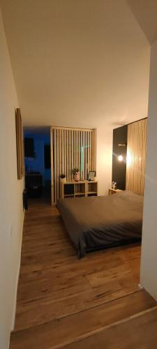 a bedroom with a large bed and a wooden floor at OasisNoir in Calonne-Ricouart
