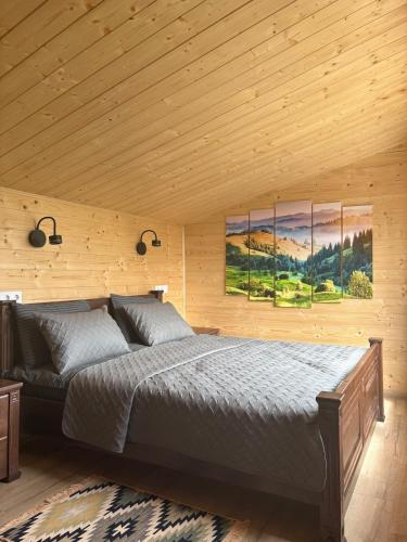 a bedroom with a bed and two paintings on the wall at Evergreen cottage in Slavske