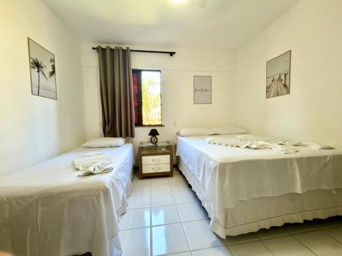 a room with two beds and a window at Flat 3 Quartos Pé na Areia, Piscina e Mar, Summer House Genipabu, Guarajuba in Guarajuba