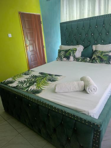 a bed with a green headboard with two towels on it at ADONAI Homes in Malindi