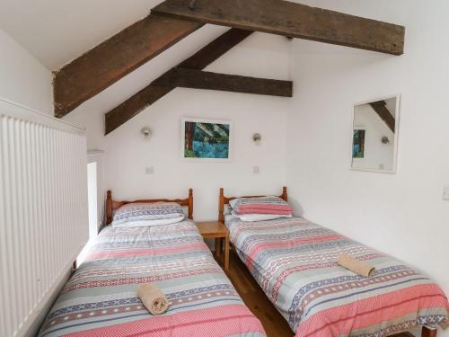 two beds in a room with white walls and wooden beams at Tegfan in Newport