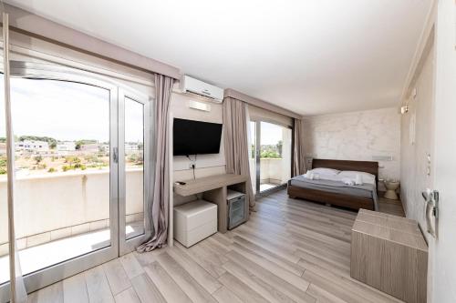 a bedroom with a bed and a tv andwindows at Hotel Aurora in Porto Cesareo