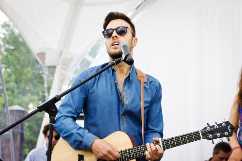 a man singing into a microphone while playing a guitar at Park Hotel in Karagandy