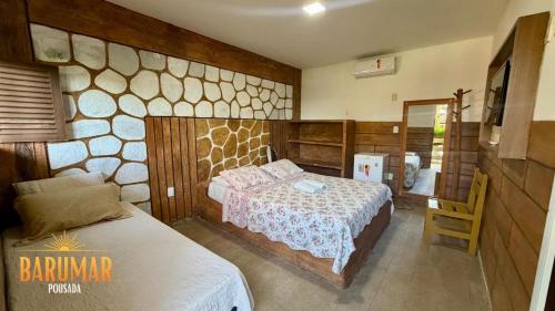 a bedroom with a bed and a stone wall at Pousada Barumar in Lucena
