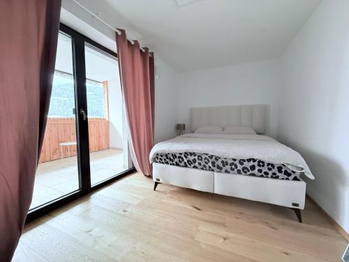 a white bedroom with a bed and a large window at Villa Vita - MELANI in Slovenj Gradec