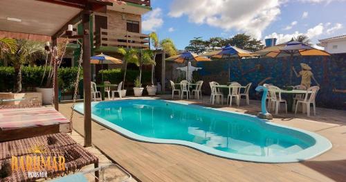 a swimming pool with tables and chairs and umbrellas at Pousada Barumar in Lucena