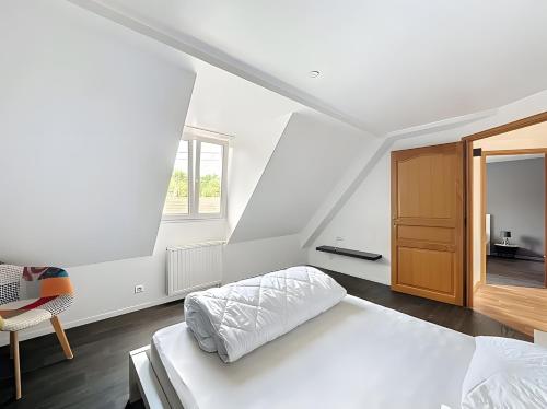 a white bedroom with a bed and a chair at Gite Loan proche Colmar in Ingersheim