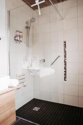 a bathroom with a shower with a black tile floor at Gästehaus Frevel in Münstermaifeld