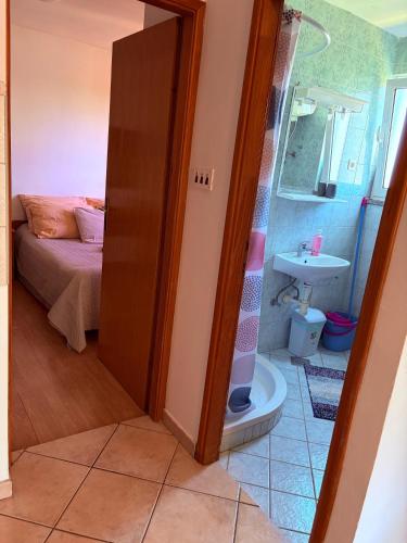 a bathroom with a shower and a bed and a sink at Apartmani Maria in Preko