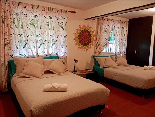 a bedroom with two beds and a window with curtains at Casa Bosco Minca in Santa Marta