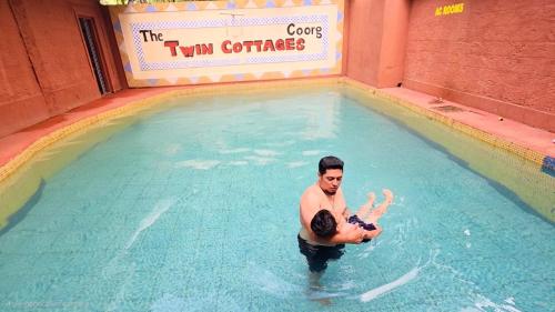 a man and a boy in a swimming pool at Twin Retreat in Madikeri