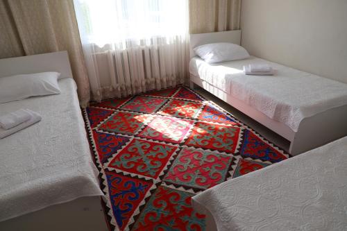 a room with two beds and a colorful carpet at Khan Dobo in Bokonbayevo