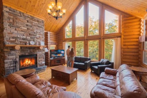a man standing in a living room with a fireplace at Fiddler Lake 72 with Private spa, pool table & Pool in Mille-Isles