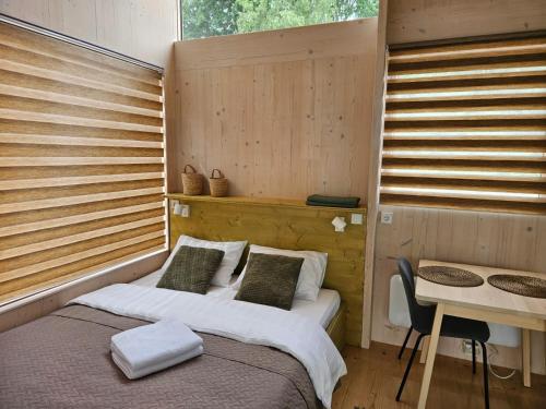 a bedroom with a bed and a table and a desk at Piestātne Riverside Cabins with Sauna, Hot Tub & Private Pier in Katlakalns