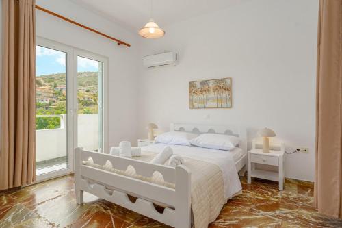 a white bedroom with a bed and a large window at R&M Ocean View in Dhaskalión