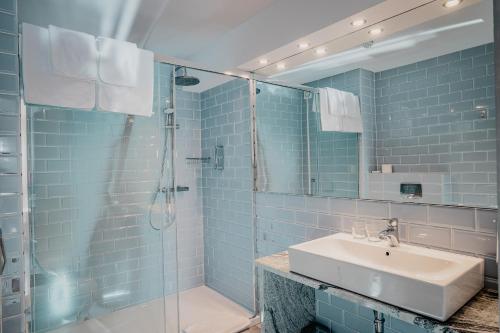 a blue tiled bathroom with a sink and a shower at Hotel Kahlberg in Krynica Morska