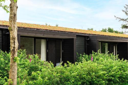 a black house with a red roof at BLÅBJERGGAARD - Hennebysvej 60 in Henne Strand