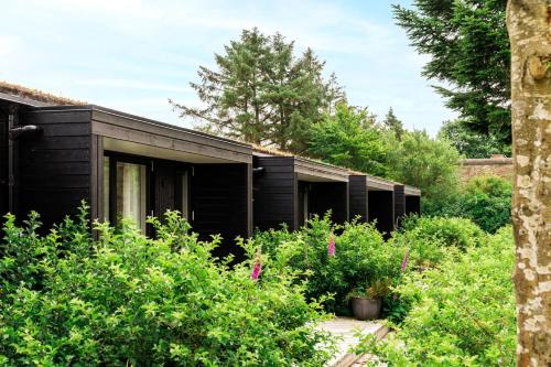 a black house with a garden in front of it at BLÅBJERGGAARD - Hennebysvej 60 in Henne Strand