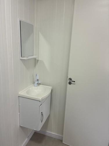 a white bathroom with a sink and a mirror at Refúgio ensolarado a poucos passos do mar in Navegantes