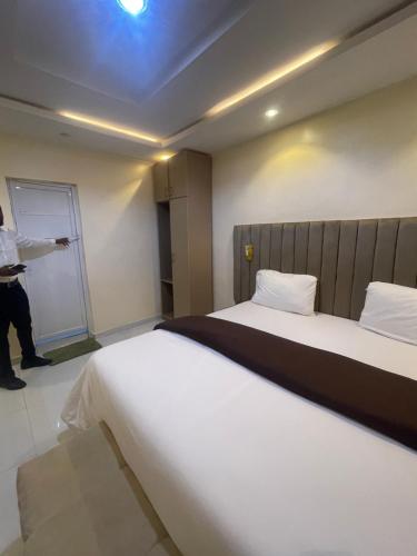 a person standing in a hotel room with two beds at CHASE hotels in Ibadan