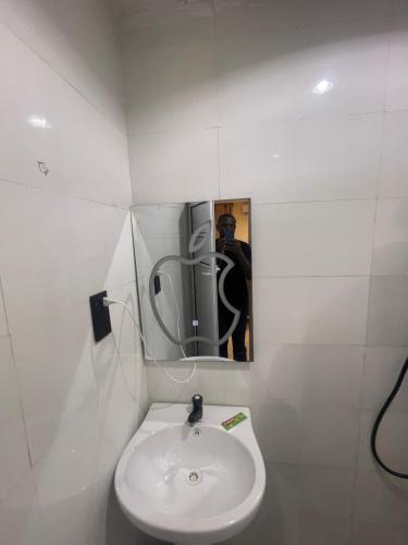 a white bathroom with a sink and a mirror at CHASE hotels in Ibadan