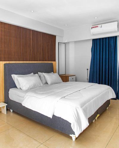 a bedroom with a large white bed with blue curtains at Solaris Luxury Residence Osu Pool Gym in Accra