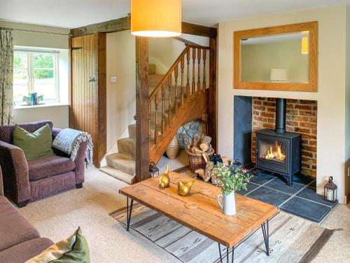 a living room with a fireplace and a table at Barters Cottage in Chideock