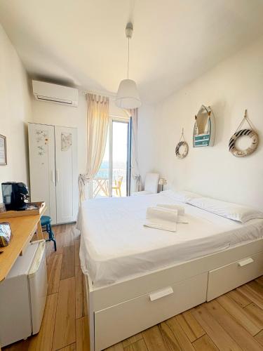 a bedroom with a large white bed with a window at Casa Maritrì Locazione Turistica in Marzamemi