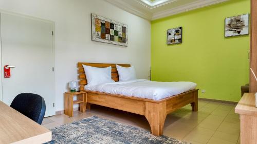 a bed in a room with a green wall at Kipress Lodge Hôtel in Ouagadougou