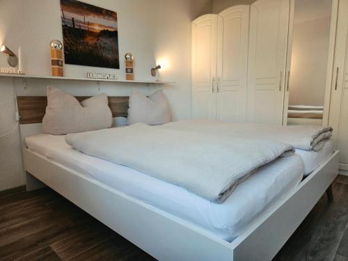 a white bedroom with a large white bed with pillows at Auszeit an der Eider in Hennstedt