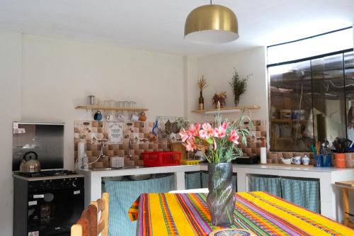 a kitchen with a table with a vase of flowers on it at Colibri Wasi Pisac in Cusco