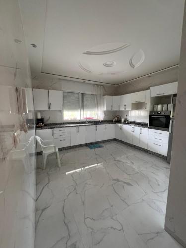 a large kitchen with white cabinets and a marble floor at Safae in Agadir