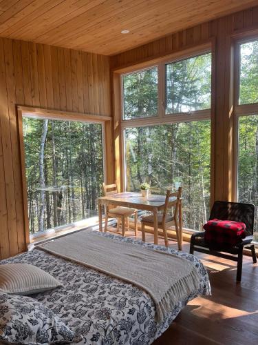 a room with a table and chairs and windows at Tanières MicroChalets Charlevoix in Baie-Saint-Paul