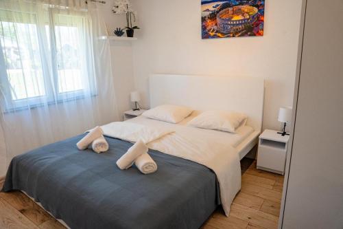 a bedroom with a large bed with towels on it at Aria garden house in Loborika