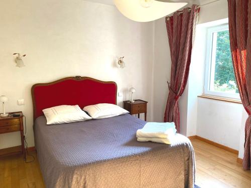 a bedroom with a bed with a red headboard and a window at Chambre dhôtes au pigeonnier in Poulan-Pouzols