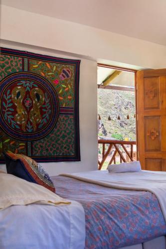 a bedroom with two beds and a window with a view at Colibri Wasi Pisac in Cusco