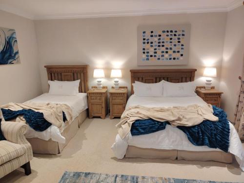 a bedroom with two beds and a chair and two lamps at Marble on 8 in Rustenburg