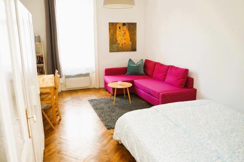 a living room with a pink couch and a table at Cozy&Quiet Apartment near Schönbrunnpalace in Vienna