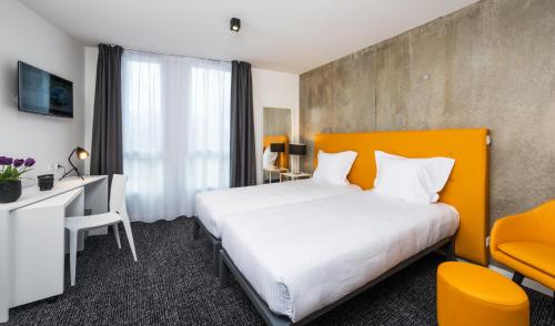 a hotel room with a large bed and a desk at Ténéo Apparthotel Talence Espeleta - Bordeaux Sud in Talence