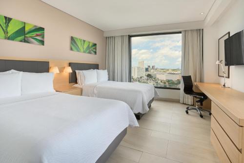 a hotel room with two beds and a desk at Fiesta Inn Mérida Altabrisa in Mérida