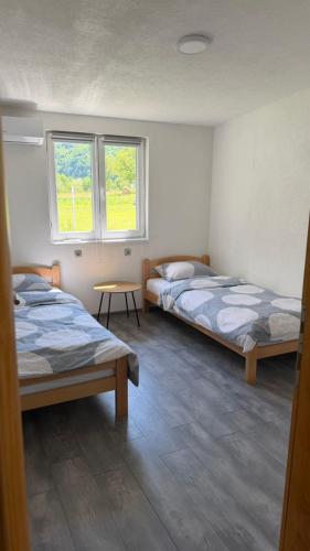 a room with two beds and a table and two windows at Villa EMELA in Jajce