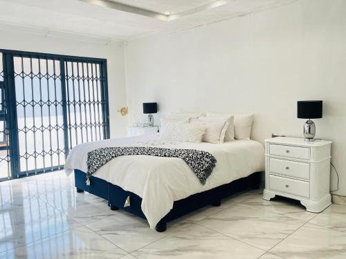 ein weißes Schlafzimmer mit Bett und Nachttisch in der Unterkunft Mafjoint in Zeerust
