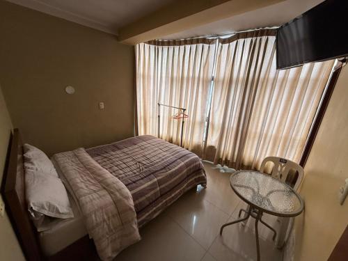 a bedroom with a bed and a table and a window at Hostal Tintaya in Cajamarca