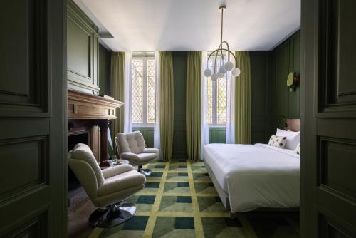 a bedroom with a bed and a chair and a fireplace at Hotel des Quinconces Bordeaux Centre in Bordeaux